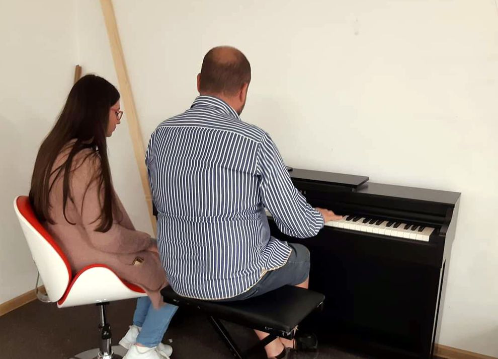 mężczyzna grający na pianinie obok młoda kobieta