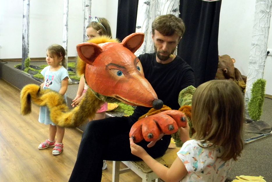 aktor z muppetem lisa Witalisa, przed nim dziewczynka dotykająca łapy, za dziecko trzymające ogon